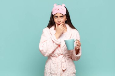 Ağzı ve gözleri açık, eli çenesinde genç ve güzel bir kadın. Hoş olmayan bir şok geçiriyor. Ne diyor? Pijama giyip uyanmak