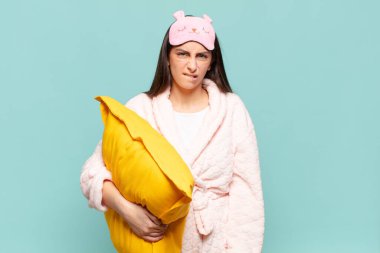 Kafası karışmış ve kafası karışmış genç bir kadın gergin bir hareketle dudağını ısırıyor, sorunun cevabını bilmiyor. Pijama giyip uyanmak