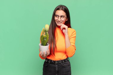 Genç, güzel bir kadın, mutlu, kendinden emin bir ifadeyle gülümsüyor, elleri çenesinde, merak ediyor ve yan tarafa bakıyor. Kaktüs kavramı