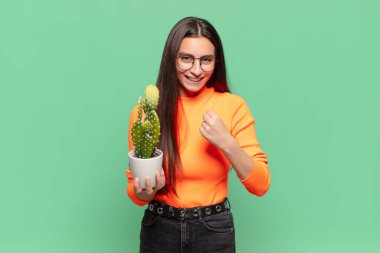Genç, güzel bir kadın şok olmuş, heyecanlı ve mutlu hissediyor, gülüyor ve başarıyı kutluyor, vay canına! Kaktüs kavramı