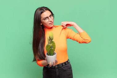 Genç, güzel bir kadın stresli, endişeli, yorgun ve hayal kırıklığına uğramış, gömleğini çekmiş, sorunlu görünüyor. Kaktüs kavramı