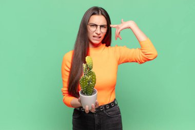 Genç, güzel bir kadın kafası karışık ve şaşkın hissediyor. Deli, deli ya da aklını kaçırmış olduğunu gösteriyor. Kaktüs kavramı