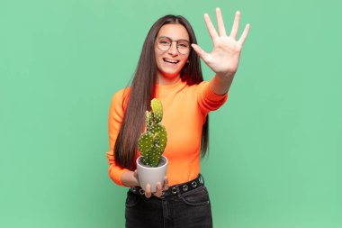 Genç ve güzel bir bayan gülümsüyor ve arkadaş canlısı görünüyor. Beş ya da beş numarayı gösteriyor. Elleri önde ve geri sayıyor. Kaktüs kavramı