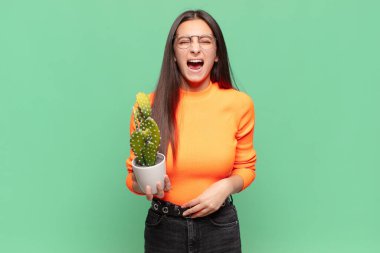 Genç ve güzel bir kadın agresif bir şekilde bağırıyor. Kızgın, sinirli ya da sinirli görünüyor. Hayır diye bağırıyor. Kaktüs kavramı