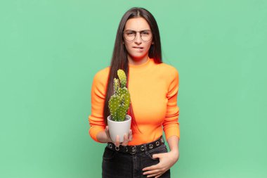 Kafası karışmış ve kafası karışmış genç bir kadın gergin bir hareketle dudağını ısırıyor, sorunun cevabını bilmiyor. Kaktüs kavramı