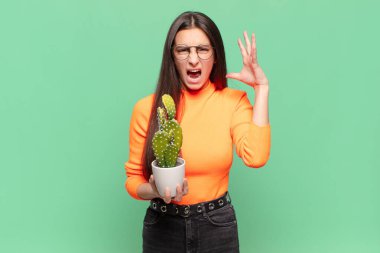 Genç ve güzel bir kadın ellerini havaya kaldırıp bağırıyor. Öfkeli, sinirli, stresli ve üzgün hissediyor. Kaktüs kavramı