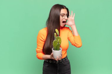 Genç, güzel bir kadın mutlu, heyecanlı ve şaşırmış hissediyor. İki eli de suratında yana bakıyor. Kaktüs kavramı