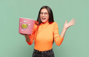 Genç, güzel bir kadın mutlu, heyecanlı, şaşırmış ya da şok olmuş hissediyor. İnanılmaz bir şeye gülümsüyor ve hayrete düşüyor. patlamış mısır konsepti