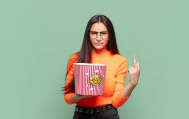 Genç ve güzel bir kadın kızgın, sinirli, isyankar ve agresif hissediyor. Orta parmağını hareket ettiriyor, karşı koyuyor. patlamış mısır konsepti