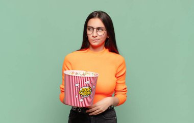 Genç, güzel bir kadın üzgün, üzgün ya da kızgın. Olumsuz bir tavırla yan yana bakıyor, anlaşmazlık içinde kaşlarını çatıyor. patlamış mısır konsepti