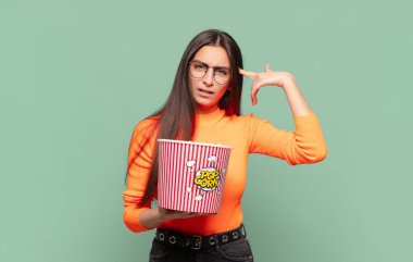 Genç, güzel bir kadın kafası karışık ve şaşkın hissediyor. Deli, deli ya da aklını kaçırmış olduğunu gösteriyor. patlamış mısır konsepti