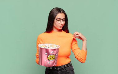 Genç ve güzel bir kadın kibirli, başarılı, pozitif ve gururlu görünüyor, kendini işaret ediyor. patlamış mısır konsepti