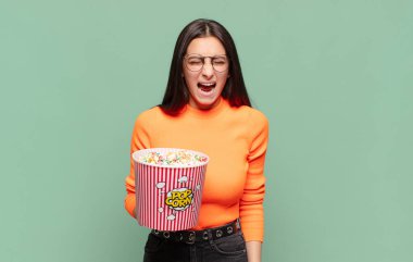 Genç ve güzel bir kadın agresif bir şekilde bağırıyor. Kızgın, sinirli ya da sinirli görünüyor. Hayır diye bağırıyor. patlamış mısır konsepti