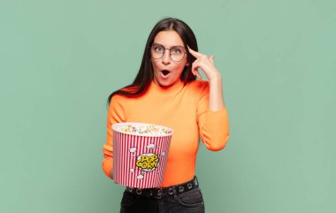 Genç, güzel bir kadın şaşırmış, ağzı açık, şok olmuş, yeni bir düşünce, fikir ya da konsept keşfediyor. patlamış mısır konsepti