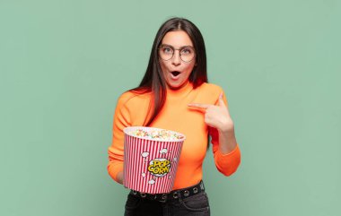 Şok olmuş ve ağzı açık, kendini gösteren genç ve güzel bir kadın. patlamış mısır konsepti