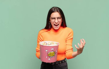 Genç ve güzel bir kadın umutsuz ve hayal kırıklığına uğramış görünüyor, stresli, mutsuz ve sinirli, bağırıyor ve çığlık atıyor. patlamış mısır konsepti