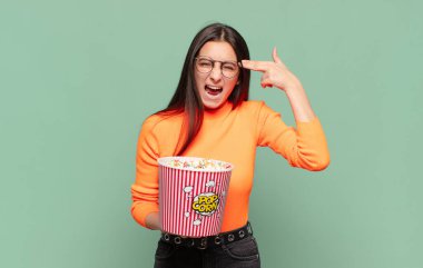 Genç ve güzel bir kadın mutsuz ve stresli görünüyor, intihar jesti, silahla işaret ediyor, kafasını işaret ediyor. patlamış mısır konsepti