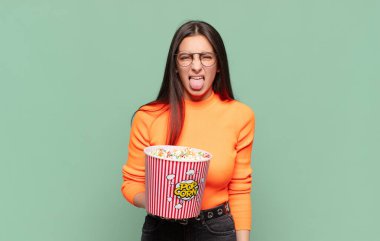 Genç ve güzel bir kadın iğrenmiş ve rahatsız olmuş hissediyor. Dilini dışarı çıkarıyor. Çirkin ve iğrenç şeylerden hoşlanmıyor. patlamış mısır konsepti