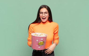 Genç, güzel bir kadın mutlu ve hoş bir şekilde şaşırmış görünüyor. Büyülenmiş ve şok olmuş bir ifadeyle heyecanlanıyor. patlamış mısır konsepti