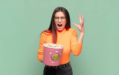 Genç ve güzel bir kadın ellerini havaya kaldırıp bağırıyor. Öfkeli, sinirli, stresli ve üzgün hissediyor. patlamış mısır konsepti