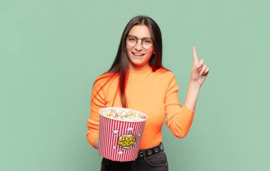 Genç ve güzel bir kadın bir fikri fark ettikten sonra mutlu ve heyecanlı bir dahi gibi hissediyor, neşeli bir şekilde parmağını kaldırıyor, eureka! patlamış mısır konsepti