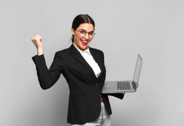 Genç, güzel bir kadın şok olmuş, heyecanlı ve mutlu hissediyor, gülüyor ve başarıyı kutluyor, vay canına! dizüstü bilgisayar