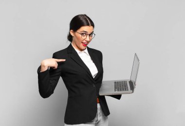 Genç, güzel bir kadın mutlu, şaşırmış ve gururlu hissediyor. Heyecanlı ve şaşkın bir bakışla kendini işaret ediyor. dizüstü bilgisayar