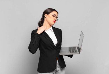 Genç, güzel bir kadın stresli, endişeli, yorgun ve hayal kırıklığına uğramış, gömleğini çekmiş, sorunlu görünüyor. dizüstü bilgisayar