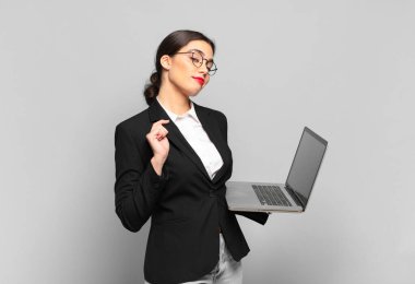 Genç ve güzel bir kadın kibirli, başarılı, pozitif ve gururlu görünüyor, kendini işaret ediyor. dizüstü bilgisayar