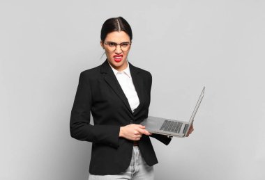 young pretty woman feeling puzzled and confused, with a dumb, stunned expression looking at something unexpected. laptop concept