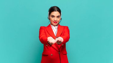 Genç, güzel bir kadın mutlu bir şekilde gülümsüyor. Dost canlısı, kendine güvenen, olumlu bakışlı, bir nesne ya da konsept sunuyor. tele pazarlamacı kavramı