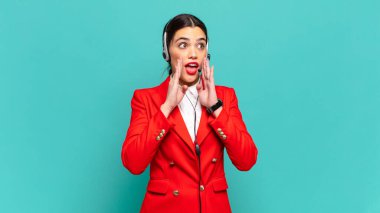 Genç, güzel bir kadın mutlu, heyecanlı ve pozitif hissediyor. Elleri ağızda, bağırarak bağırıyor. tele pazarlamacı kavramı