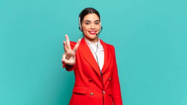 Genç, güzel bir bayan gülümsüyor ve arkadaş canlısı görünüyor. Üç ya da üç numarayı gösteriyor. Elleri önde, geriye doğru sayıyor. tele pazarlamacı kavramı