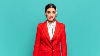 Kafası karışmış ve kafası karışmış genç bir kadın gergin bir hareketle dudağını ısırıyor, sorunun cevabını bilmiyor. tele pazarlamacı kavramı