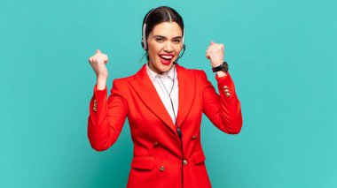 Genç ve güzel bir kadın öfkeli bir ifadeyle ya da yumruklarıyla başarıyı kutlarken agresif bir şekilde bağırıyor. tele pazarlamacı kavramı