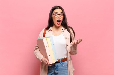 Genç ve güzel bir kadın ağzı açık ve şaşırmış, şok olmuş ve hayrete düşmüş inanılmaz bir sürprizle. öğrenci konsepti