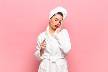 Genç ve güzel bir kadın yorgun, sıkıcı ve can sıkıcı bir işten sonra sıkılmış, hayal kırıklığına uğramış ve uykulu hissediyor, el ele tutuşarak. Bornoz ve diş fırçası kavramı