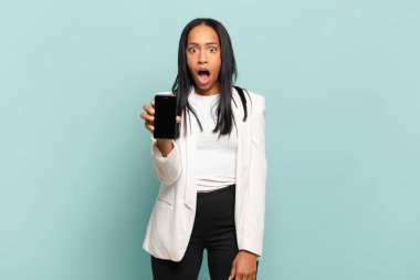 Genç siyahi kadın şok olmuş ya da şaşırmış görünüyor, ağzı açık bir şekilde 