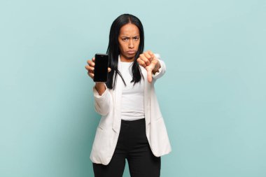 Genç siyahi kadın kızgın, sinirli, hayal kırıklığına uğramış ya da hoşnutsuz hissediyordu. Ciddi bir bakışla baş parmağını aşağı gösteriyordu. akıllı telefon kavramı