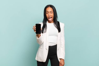 Genç siyah kadın neşeli, kaygısız, asi tavırlı, şakacı ve dilsiz, eğleniyor. akıllı telefon kavramı