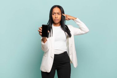 Genç siyahi kadın kafası karışık ve şaşkın hissediyor. Deli, deli ya da aklını kaçırmış olduğunu gösteriyor. akıllı telefon kavramı