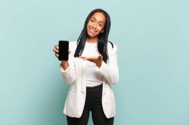 Genç siyahi kadın neşeyle gülümsüyor, mutlu hissediyor ve fotokopi uzayı içinde avucunun içi gibi bir konsept gösteriyor. akıllı telefon kavramı