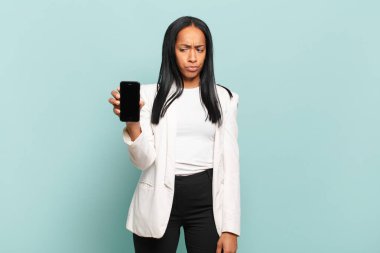Genç siyahi kadın üzgün, üzgün ya da kızgın hissediyordu ve olumsuz bir tavır sergiliyordu, anlaşmazlık içinde kaşlarını çatıyordu. akıllı telefon kavramı
