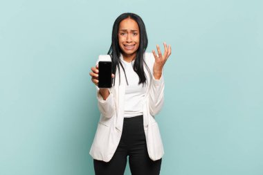 Genç siyahi kadın umutsuz ve sinirli görünüyor, stresli, mutsuz ve sinirli, bağırıyor ve çığlık atıyor. akıllı telefon kavramı