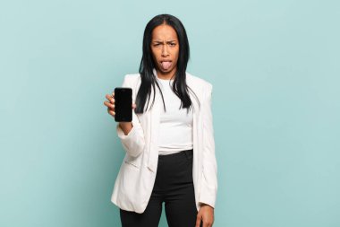 Genç siyahi kadın tiksinmiş ve rahatsız olmuş hissediyor. Dilini dışarı çıkarıyor. İğrenç ve iğrenç bir şeyden hoşlanmıyor. akıllı telefon kavramı