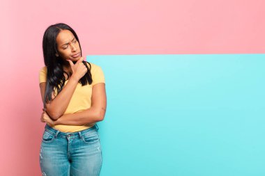 Genç siyahi kadın düşünüyor, kuşkulu ve şaşkın hissediyor, farklı seçeneklerle, hangi kararı vereceğini merak ediyor. boşluk konseptini kopyala