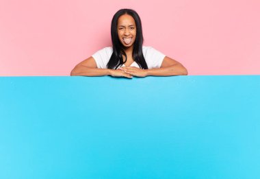 Genç siyahi kadın tiksinmiş ve rahatsız olmuş hissediyor. Dilini dışarı çıkarıyor. İğrenç ve iğrenç bir şeyden hoşlanmıyor. boşluk konseptini kopyala