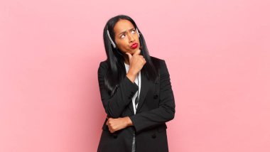 Genç siyahi kadın düşünüyor, kuşkulu ve şaşkın hissediyor, farklı seçeneklerle, hangi kararı vereceğini merak ediyor. tele pazarlama kavramı