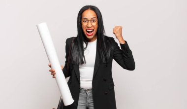 Genç siyahi kadın öfkeli bir ifadeyle ya da başarıyı kutlayan yumruklarıyla agresif bir şekilde bağırıyor. mimar konsepti