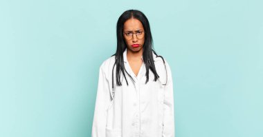 Genç siyahi kadın üzgün ve mızmızlanıyor. Mutsuz bir bakışla. Olumsuz ve hayal kırıklığına uğramış bir tavırla ağlıyor. hekimlik kavramı